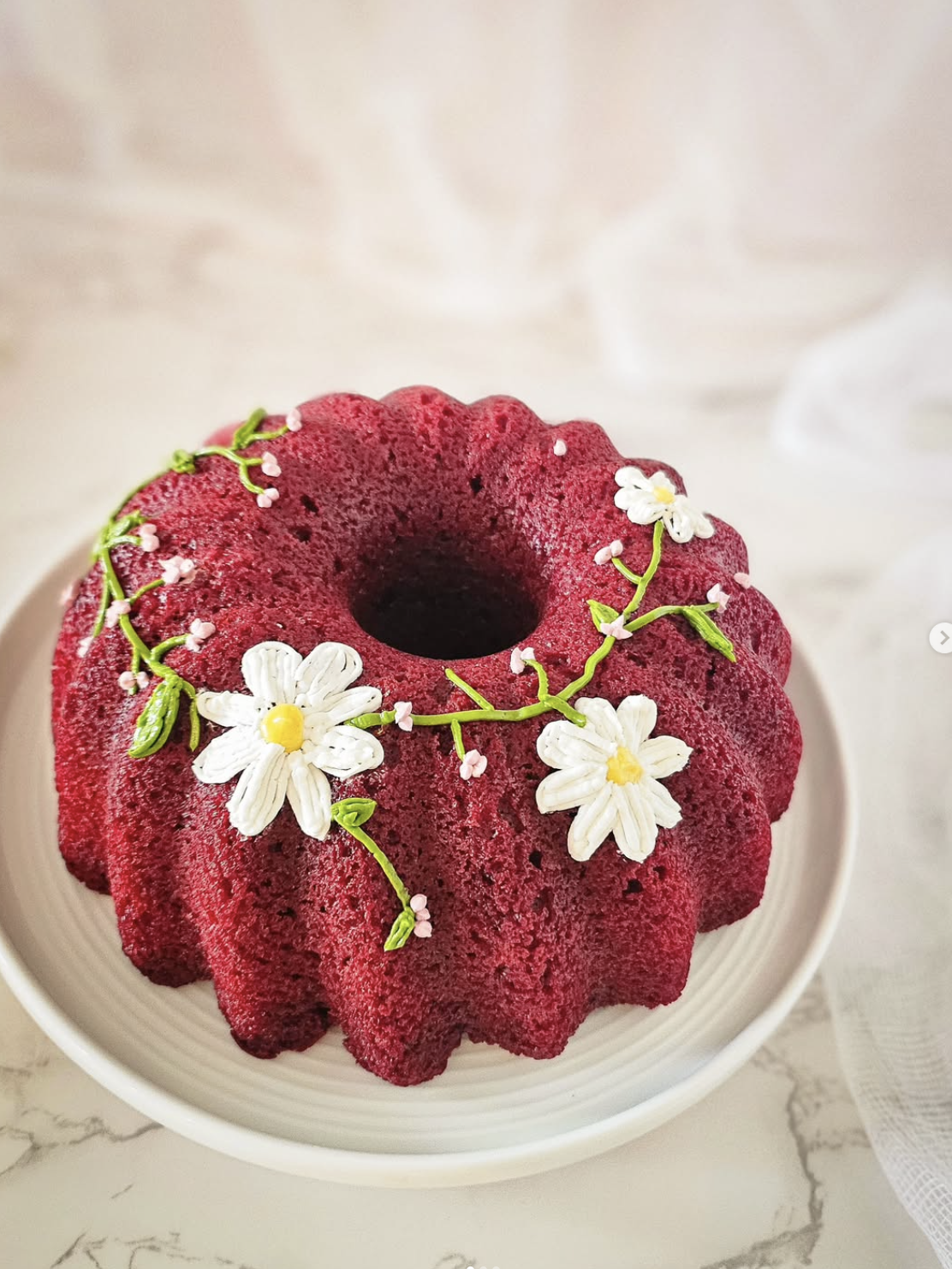 Red velvet bundt cake decorated with buttercream daisies, by Jeany Cake